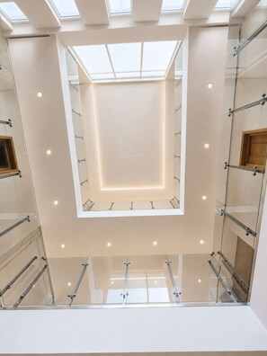 A modern interior with a central skylight, glass railings, and a minimalist design.