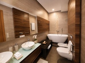 Un baño moderno con una bañera independiente, dos lavamanos, un espejo grande y paneles de madera en las paredes.