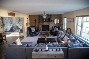 Ein Wohnzimmer mit Kamin aus Stein, Ledersofas, einem Couchtisch und einem großen Fenster.