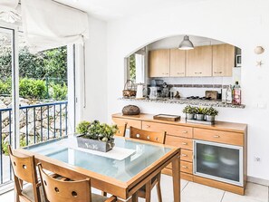 Eine moderne Küche mit Holzausstattung, einem Glastisch und Blick auf den Garten.