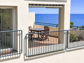 Un balcon avec une table et des chaises, donnant sur la mer.