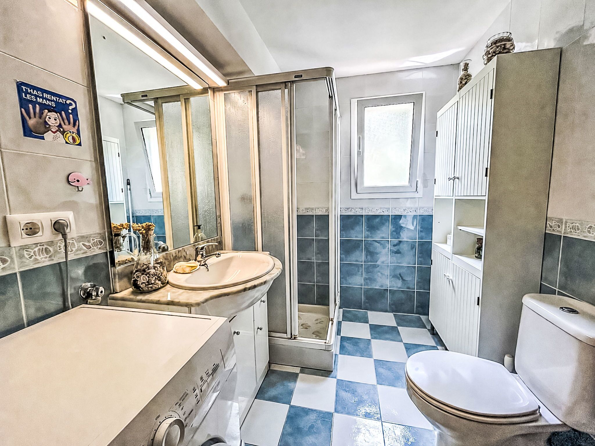 Een badkamer met een wastafel, spiegel, toilet en douche.