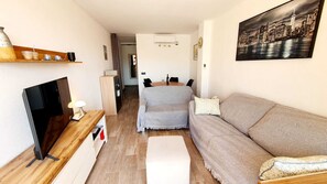 A compact living space with a sofa, a TV, a small table with a lamp, and a painting of a cityscape. - Exclusive penthouse in the center with large terrace and magnificent views (Calpe)