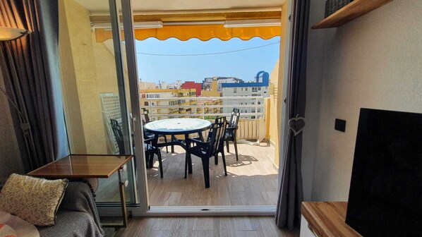 Ein Balkon mit Tisch, Stühlen, einer Couch und Blick auf Gebäude.