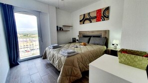 A hotel room with a large bed, a bedside table, a nightstand, a window with curtains, a view of the outside, and a wall art piece. - Exclusive penthouse in the center with large terrace and magnificent views (Calpe)