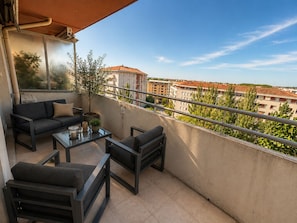 Ein Balkon mit einer Couch, Stühlen, einem Tisch und einem Blumentopf.