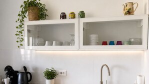 Et moderne køkken med indbygget ovn, kaffemaskine, vask og bordplade.
