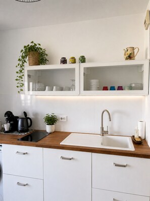 Eine moderne Küche mit Einbauofen, Kaffeemaschine, Spüle und Arbeitsplatte.