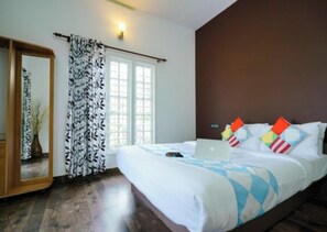 Une chambre Ă coucher avec un lit, un ordinateur portable, un miroir et une fenĂȘtre avec des rideaux.