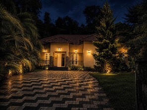 Ein zweistöckiges Haus mit Ziegeldach, einer Veranda und einem gepflasterten Auffahrt.