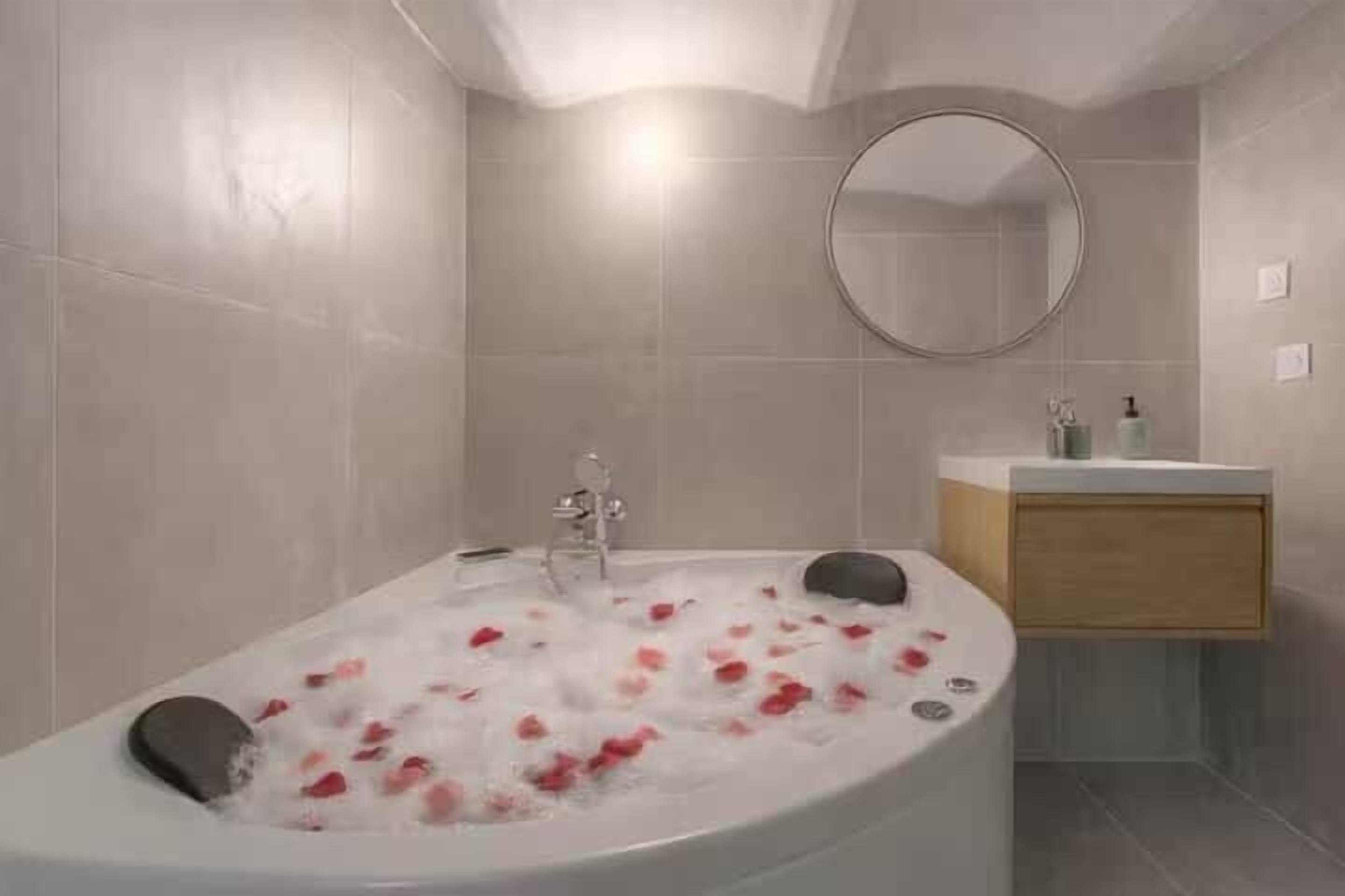 Un baño moderno con una bañera independiente, un espejo redondo y un tocador de madera.