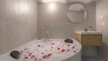 Un baño moderno con una bañera independiente, un espejo redondo y un tocador de madera.