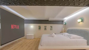 Een moderne slaapkamer met een bed, een wandtelevisie en een klein nachtkastje.