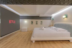 A modern bedroom with a bed, a wall-mounted TV, and a small bedside table. - Jacuzzi & Cinema - Design Loft - Lyon Gateway (Caluire-et-Cuire)