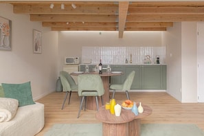 Un salon moderne comprenant un coin repas, une cuisine et un plafond en bois.
