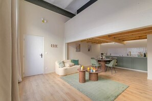 A modern apartment with a dining area, kitchen, and a living room with a sofa and coffee table. - Jacuzzi & Cinema - Design Loft - Lyon Gateway (Caluire-et-Cuire)