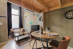 Ein gemütliches Wohnzimmer mit einem runden Holztisch, Ledersesseln, einer Couch und einer Uhr an der Wand.