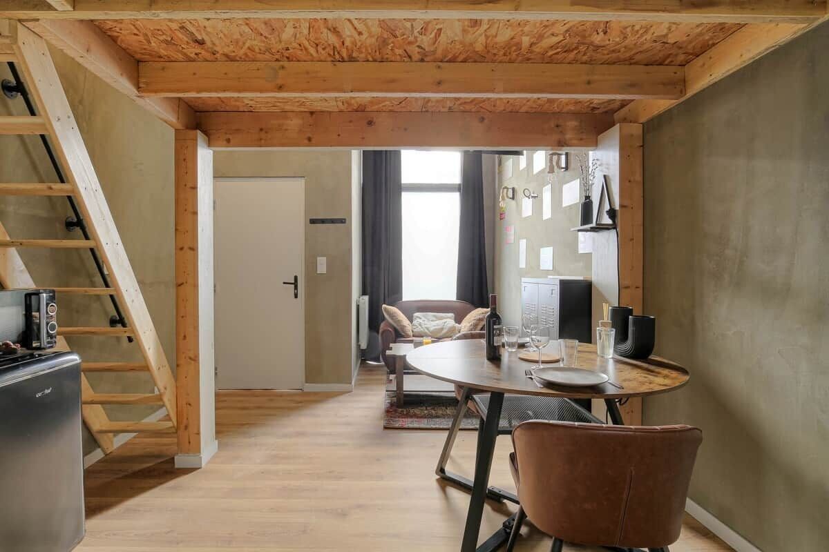 Un espace de vie compact comprenant un coin repas, une cuisine et un escalier.