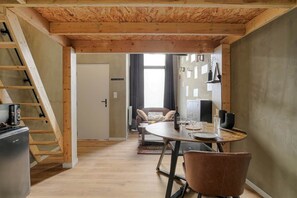 Un espacio habitable compacto con comedor, cocina y escalera.