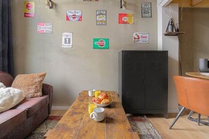 Ein Zimmer mit einem Holztisch, einer Couch, einem schwarzen Schrank und verschiedenen Markenschildern an der Wand.