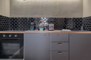 Una cocina moderna con horno empotrado, hervidor, cafetera y tostadora sobre una encimera de madera.