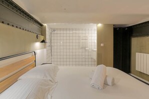 Et hotelværelse med en seng, bruser og radiator.