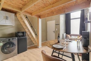 Une cuisine compacte équipée d’un lave-linge, d’un four à micro-ondes et d’un coin repas avec une table dressée pour deux personnes.