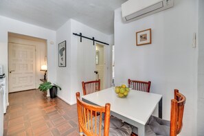 A dining area with a white table, wooden chairs, a bowl of fruit, a potted plant, and a door leading to another room. - LXR Puebloblanco 2-Bedroom Near the Sea (Torremolinos)