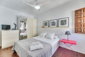 A bedroom with a bed, a desk, a mirror, and framed artwork on the wall. - LXR Puebloblanco 2-Bedroom Near the Sea (Torremolinos)