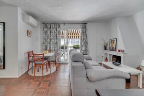 A modern living room with a sofa, dining table, chairs, and a fireplace. - LXR Puebloblanco 2-Bedroom Near the Sea (Torremolinos)