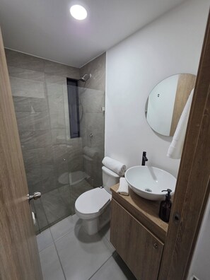Een moderne badkamer met een douchecabine, een toilet en een wastafel met een spiegel erboven.
