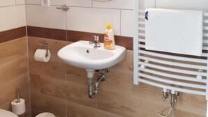 A bathroom with a white sink, mirror, and towel rack. - Berghotel (Bad Oeynhausen)