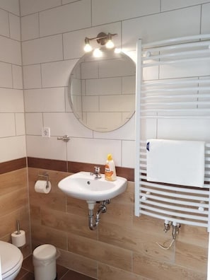 A bathroom with a white sink, mirror, and towel rack. - Berghotel (Bad Oeynhausen)