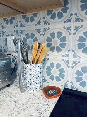 Eine Küche mit einem gemusterten Rückspritzschutz, einem Toaster, einer Gewürzregal und einer Schüssel mit spiralförmigem Muster.