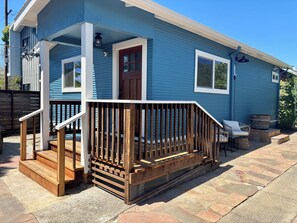 Ein blaues Haus mit einer Holzterrasse, einer Haustür und einer kleinen Veranda mit Stufen.
