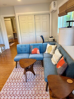 Ein Wohnzimmer mit blauem Sofa, Holztisch und gemustertem Teppich.