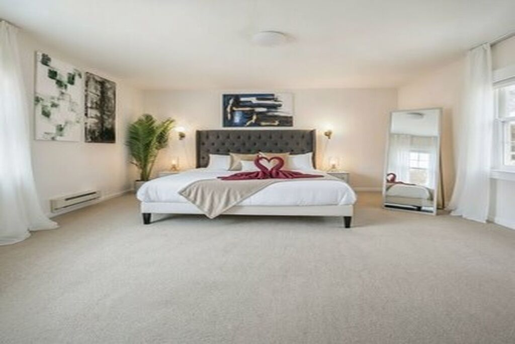 A bedroom with a bed, bedside tables, a mirror, and artwork on the walls.