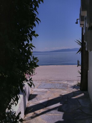 A stone pathway leading to a beach with a clear view of the sea and distant mountains. - Orsiida Seaside Cottage<br>K.Gatzea (Kato Gatzea)