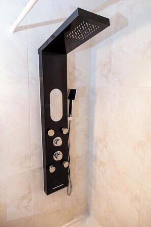 Um chuveiro moderno com múltiplas cabeças de hidrante e chuveiro manual, fixado numa parede com revestimento de azulejos.