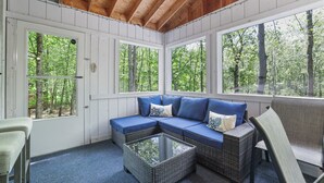 Eine überdachte Veranda mit einem Ecksofa, einem Glastisch und einem Sessel.