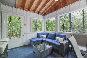 A covered porch with a sectional sofa, a glass coffee table, and a chair. - Little Bear Hideout Sauna, Game Room & Firepit (Lake Ariel)