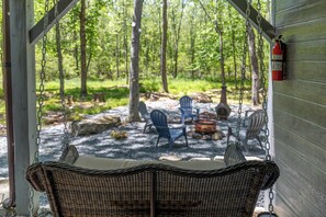 A wicker swing chair, outdoor seating, and a fire extinguisher on a wooden structure. - Little Bear Hideout Sauna, Game Room & Firepit (Lake Ariel)