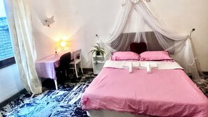 A bedroom with a canopy bed, a desk with a lamp, and a chair.
