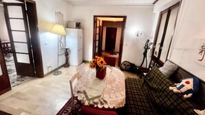 A compact living space with a dining table, a sofa, a lamp, and a small kitchenette.