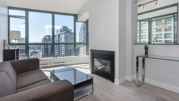 A modern living room with a fireplace, large windows, and a glass coffee table. - 2 Bed 2 Bath Free Parking Downtown Vancouver (Vancouver)