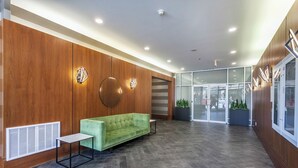 A lobby with a green sofa, a small table, wooden paneling, and a glass entrance. - 2 Bed 2 Bath Free Parking Downtown Vancouver (Vancouver)
