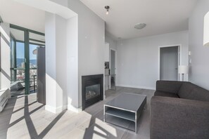 Un salon moderne avec une cheminée, un canapé, une table basse et une porte vitrée donnant sur un balcon.