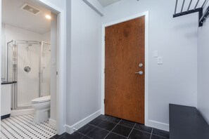 Et badeværelse med bruser, toilet og en trædør.