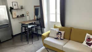 Ein gemütlicher Wohnraum mit Küchenzeile, Essbereich und einer Couch mit Zierkissen.