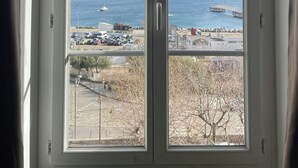 Ein Fenster mit Blick auf eine Küstenlandschaft, einschließlich eines Gewässers, einer Brücke und einem Parkplatz.